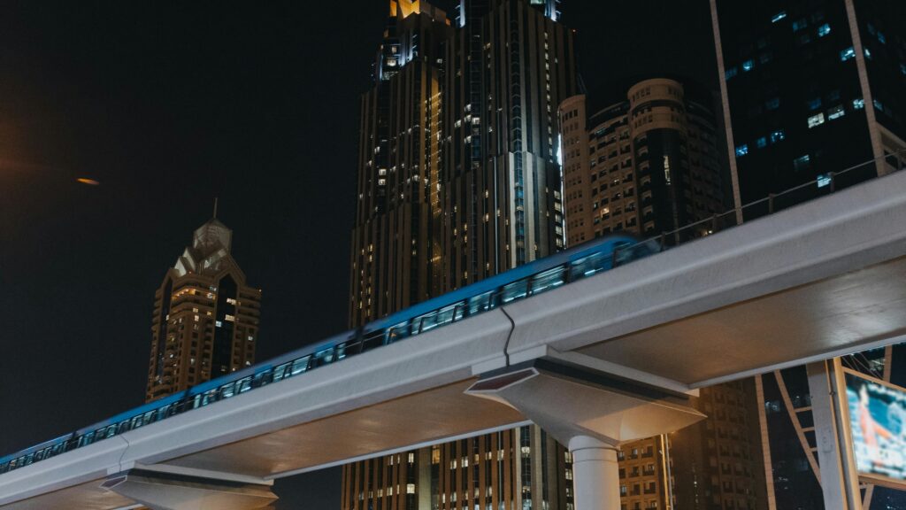 A modern train glides through a vibrant urban cityscape, framed by towering skyscrapers at night. Captivating and dynamic.
