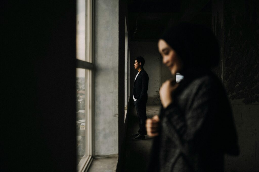 Candid image of a man and woman by a window in Makassar, creating a thoughtful atmosphere.