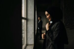 Candid image of a man and woman by a window in Makassar, creating a thoughtful atmosphere.